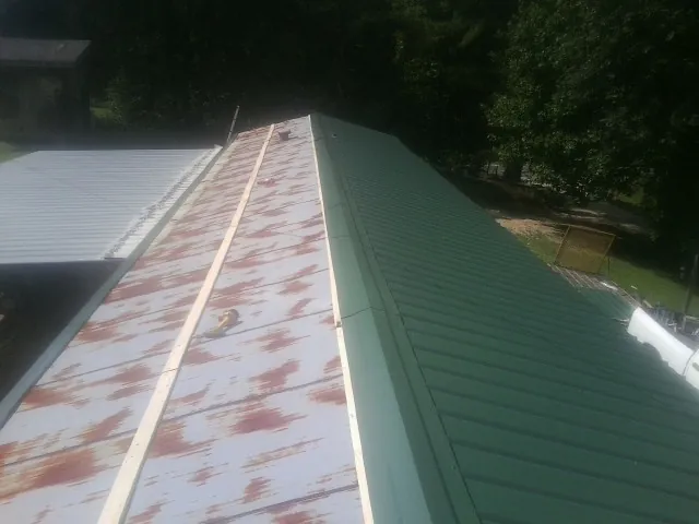Old rusted panels beside newly installed green metal roofing — Wind Damage Roof Repair by Roofing Brothers in Peotone