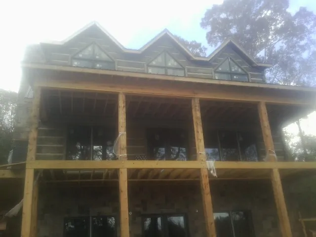 Dormers and porch framing on a large log home under construction — Roof Coating work by our crew in Peotone