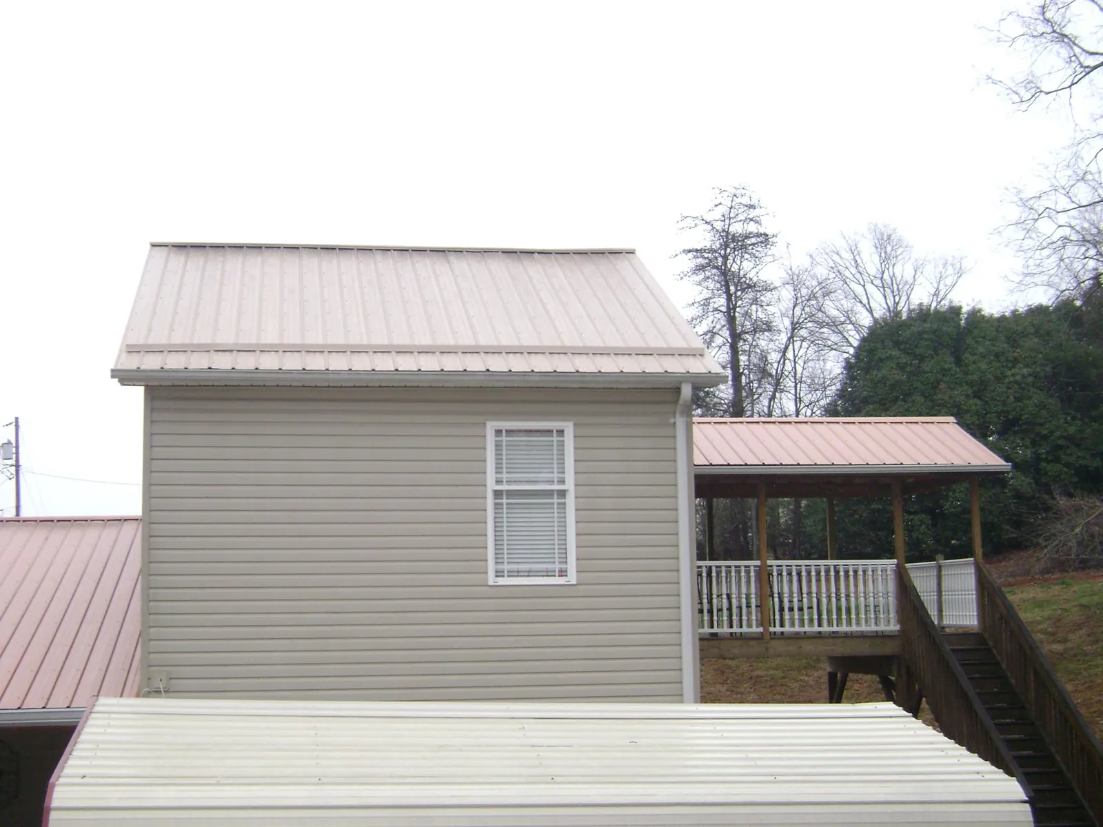 Tan metal roofs on a two story addition and attached porch, from a Roof Replacement job in Peotone