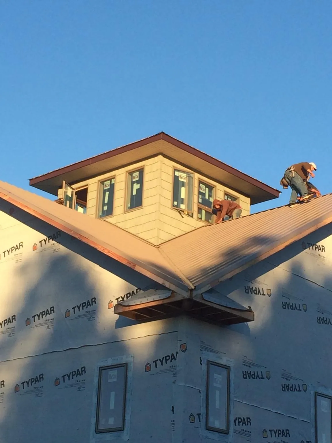 Roofers working around a rooftop cupola on a new metal roof at sunset — Roof Waterproofing in Peotone by Roofing Brothers